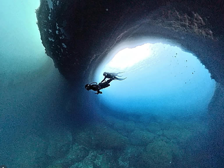 Freediver silhouetted against the entrance to Cathedral Cave, Gozo